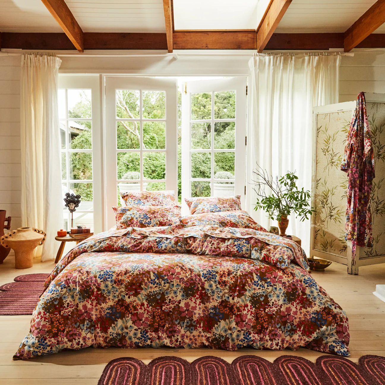 Bedroom with floral bedding and large windows.