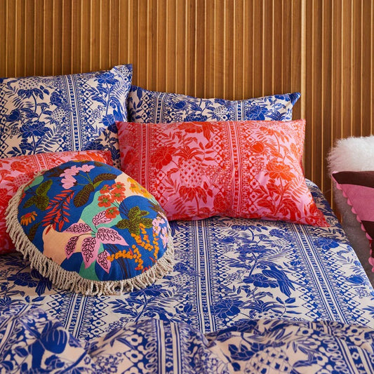 Colorful pillows and a round cushion on a bed with a patterned headboard.