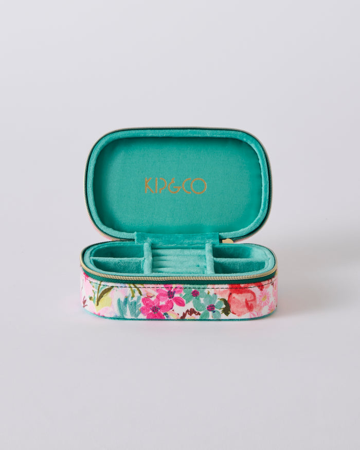 An open KIP&CO jewelry case with a turquoise velvet interior and a floral patterned exterior, shown on a light gray background.