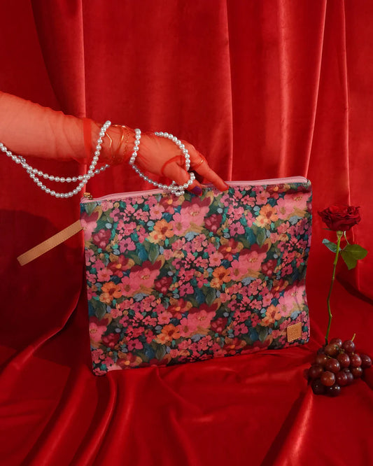 Floral-patterned pouch held by a hand against a red curtain background