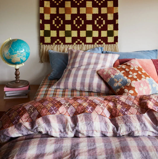Bed with patterned bedding and pillows, globe on nightstand, and tapestry on wall.