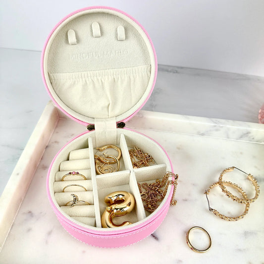 Pink jewelry box with gold jewelry on a marble surface