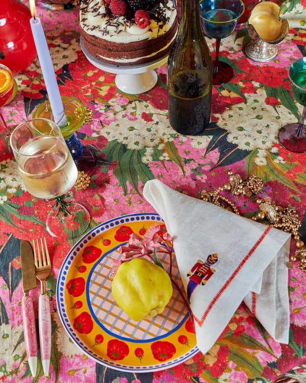 Bush blossom tablecloth laid out on table with tomato plates, wine glasses and cake stand.