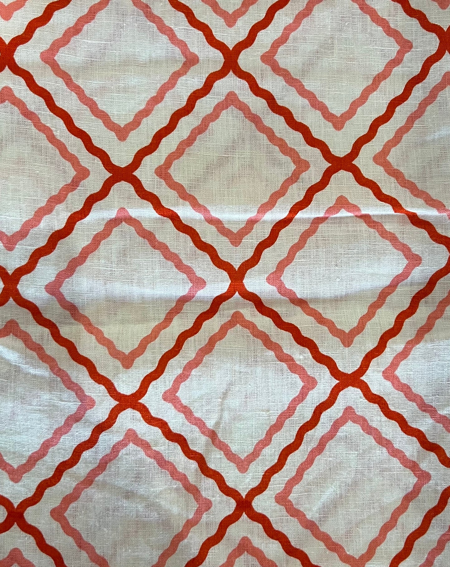 Fabric with red and pink geometric pattern on a beige background