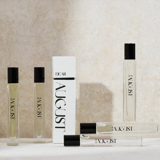 Collection of August perfume bottles and packaging on a neutral background