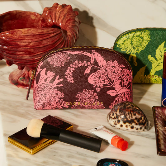 Floral-patterned makeup bag on a table with makeup items and decorative objects.