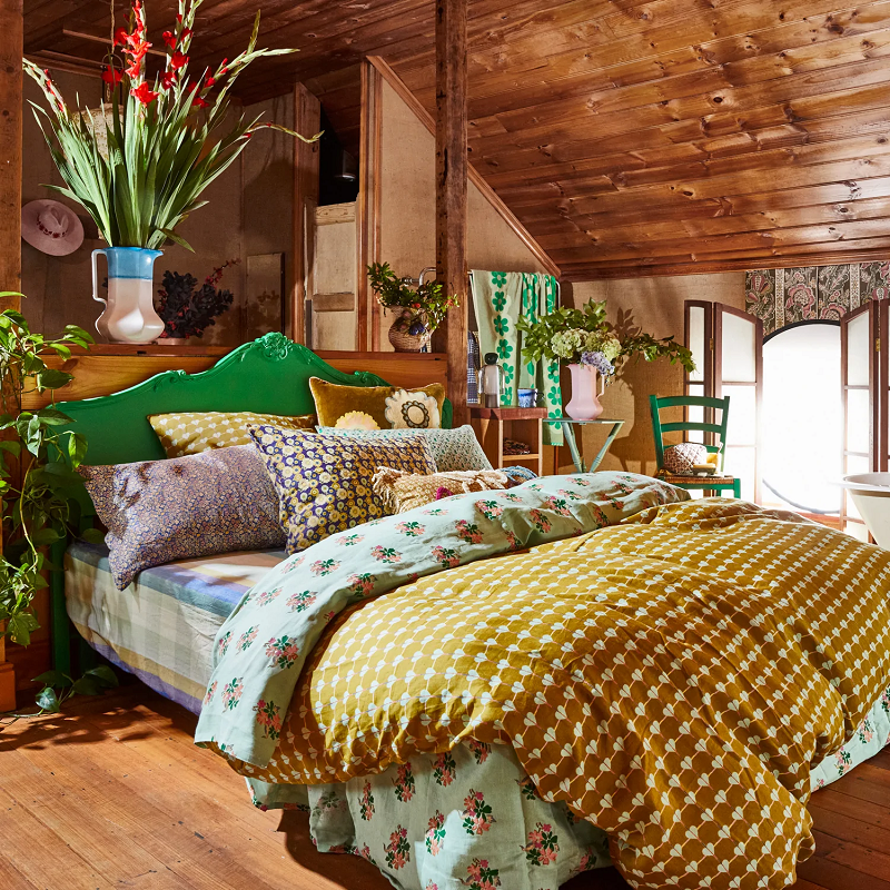 Bedroom with wooden ceiling and walls, featuring a bed with colorful bedding and decorative pillows.