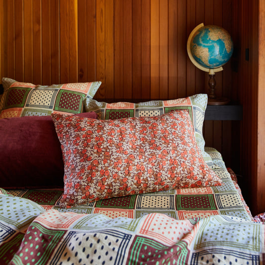Bed with patterned pillows and quilt against a wooden wall with a globe.