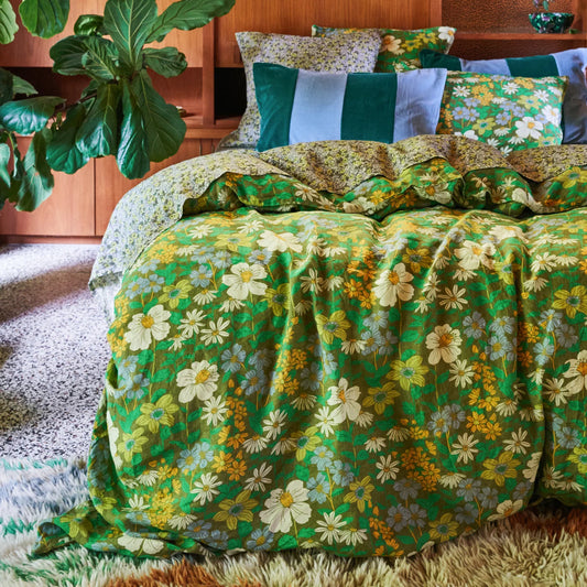 Floral bedding set on a bed in a room with plants.