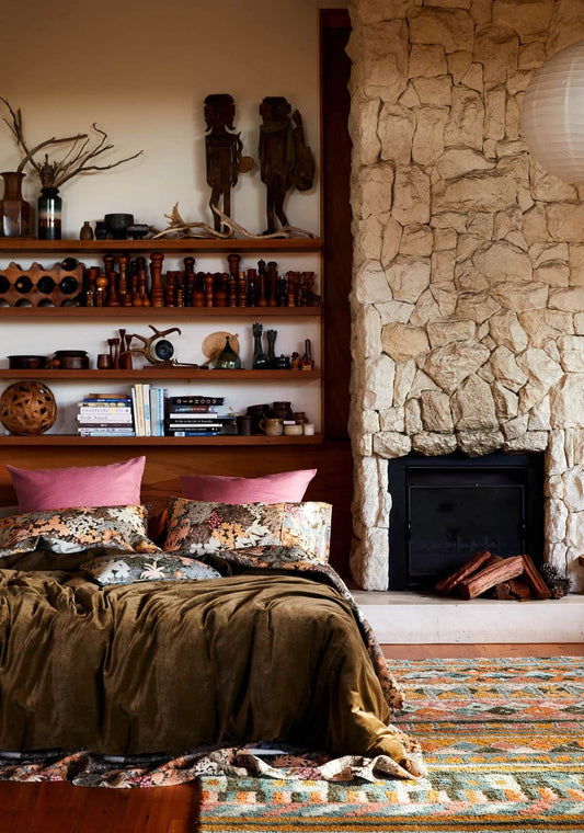 Bedroom with stone fireplace and decorative shelves.