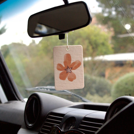 Car air freshener with a floral design hanging from the rearview mirror.