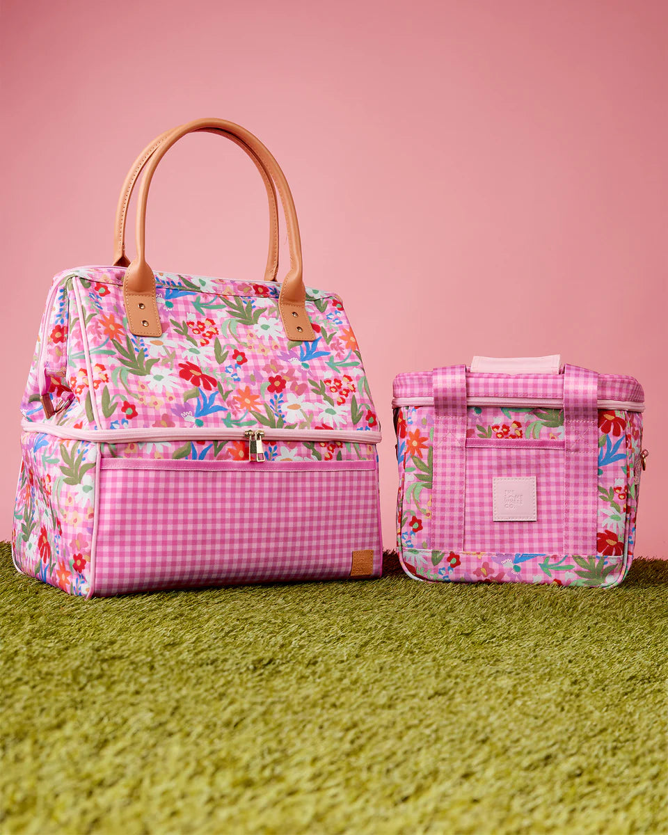 Floral-patterned handbag and cooler bag on a pink and green background
