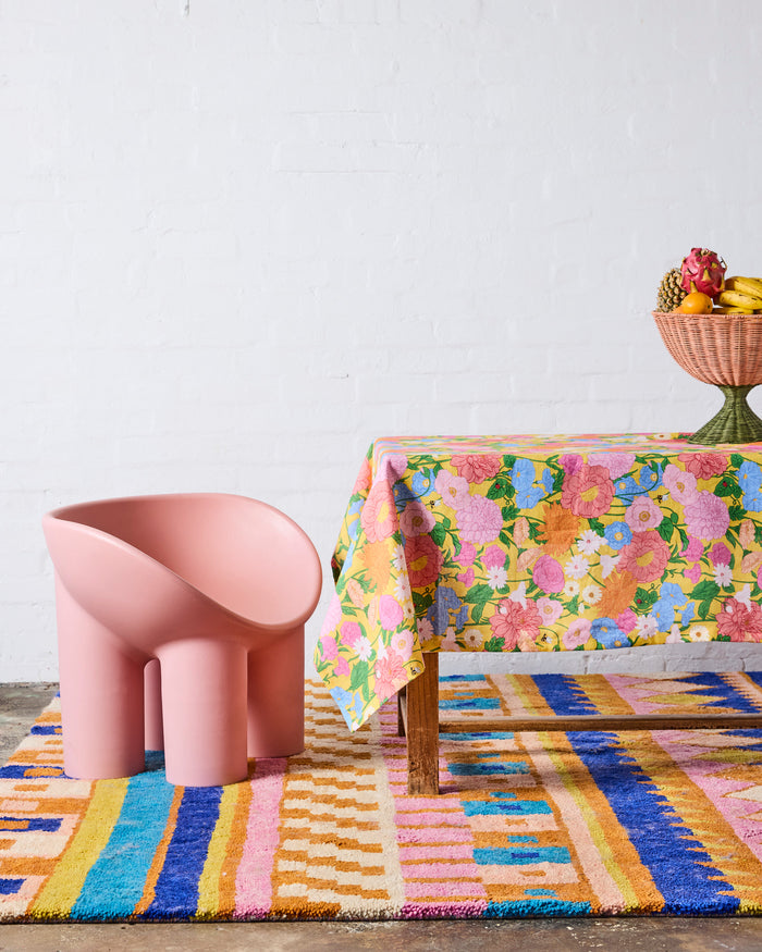 Colorful rug with a pink chair and floral tablecloth on a white background