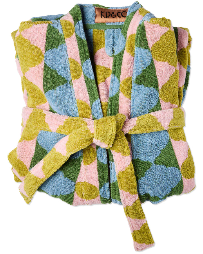 A folded terry cloth robe with a tie belt, featuring a colorful geometric pattern of pink, light blue, olive green, and mustard yellow shapes. The brand name 'KIP&CO' is visible on the inner neck label.