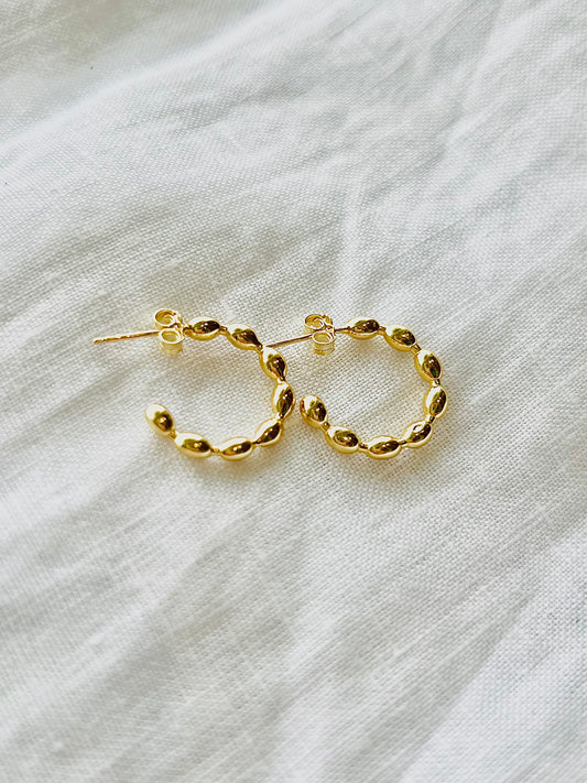 Gold hoop earrings on a white fabric background