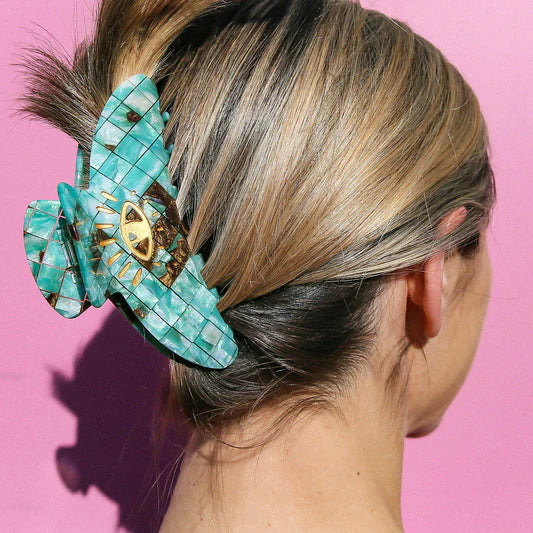 Green claw clip in long blonde hair, showing grip at back of womans head.