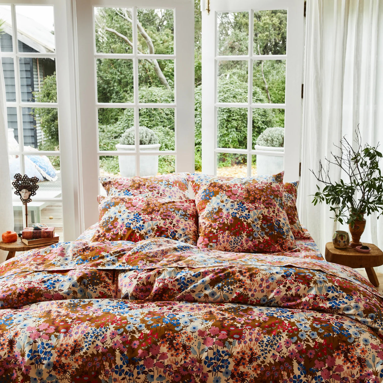Floral bedding set in a bright room with large windows.