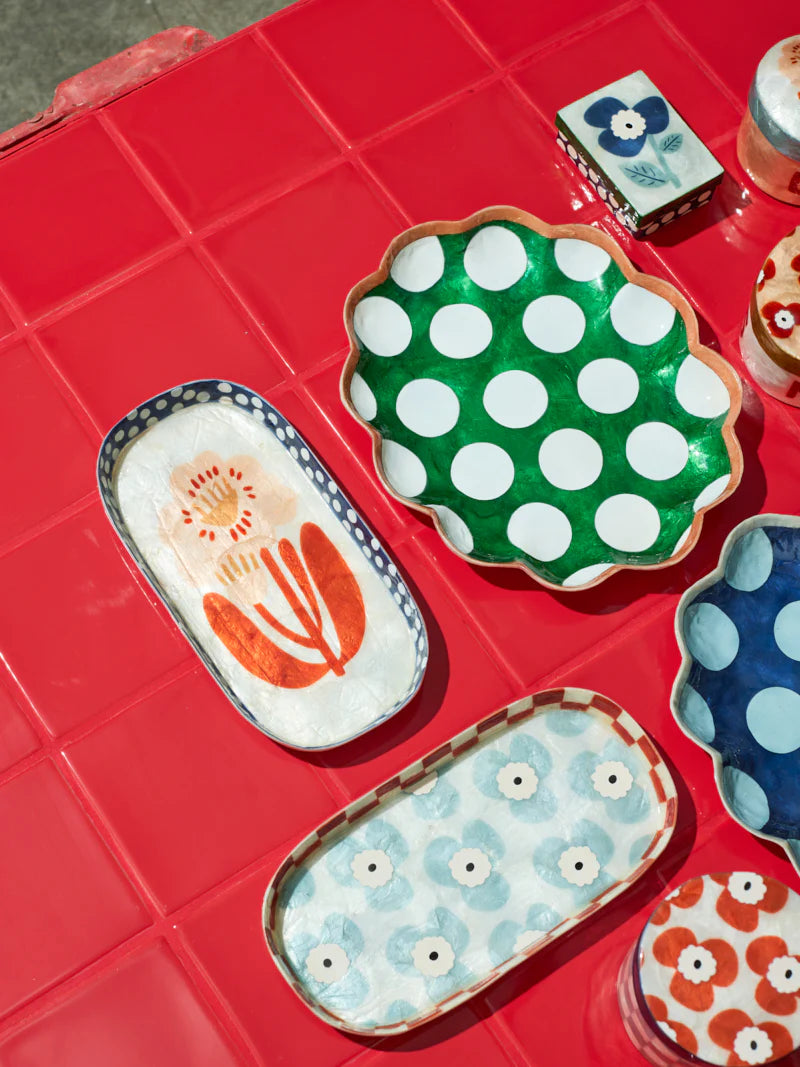 Decorative ceramic plates with floral and polka dot patterns on a red surface