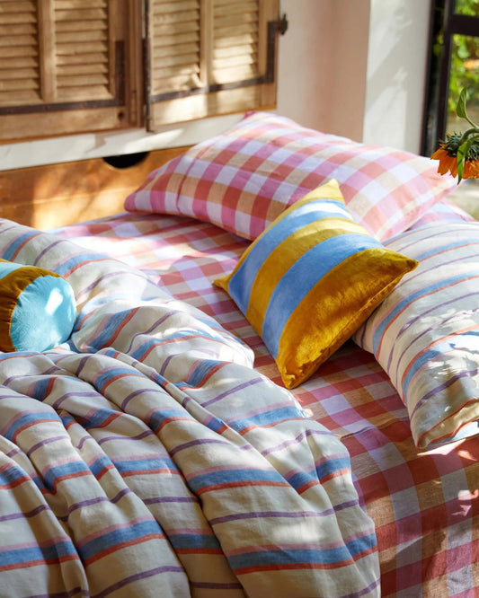 Colorful bedding with striped comforter and checkered pillows on a bed.