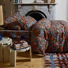 Patterned floral bedlinen in a room with a fireplace.