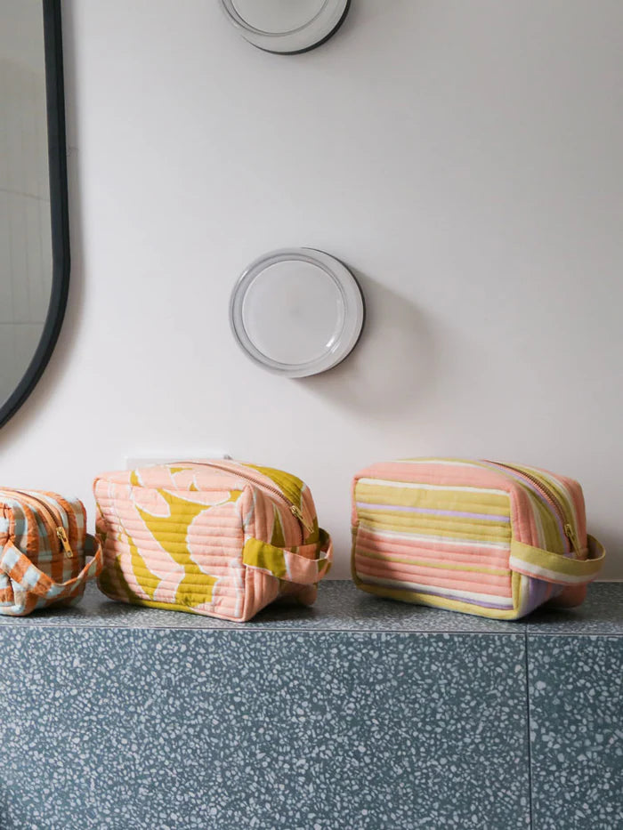 Three striped fabric bags on a speckled countertop with a mirror in the background.