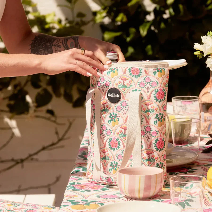 Person opening a floral-patterned cooler bag on a table with a blurred background