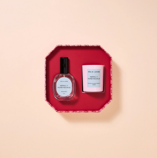 Two products, a room spray and a candle, on a red tray with a beige background