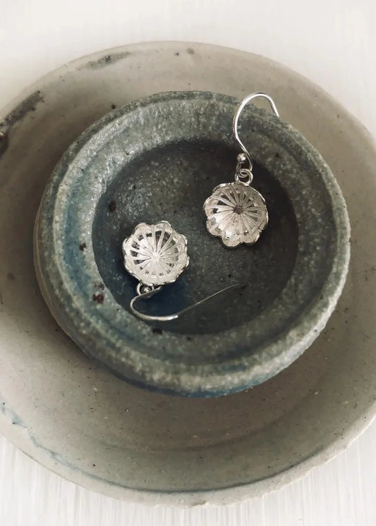 Silver earrings on a textured ceramic dish