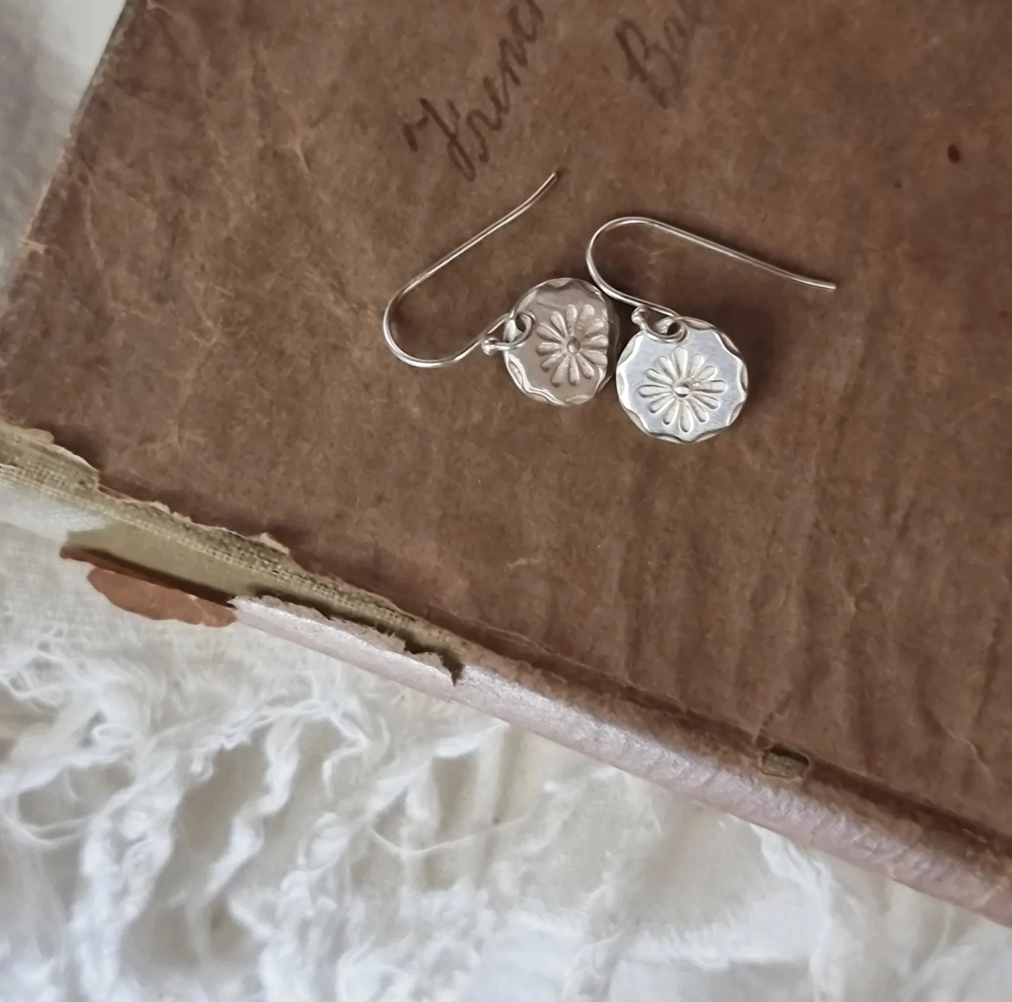 Silver earrings on a textured brown surface