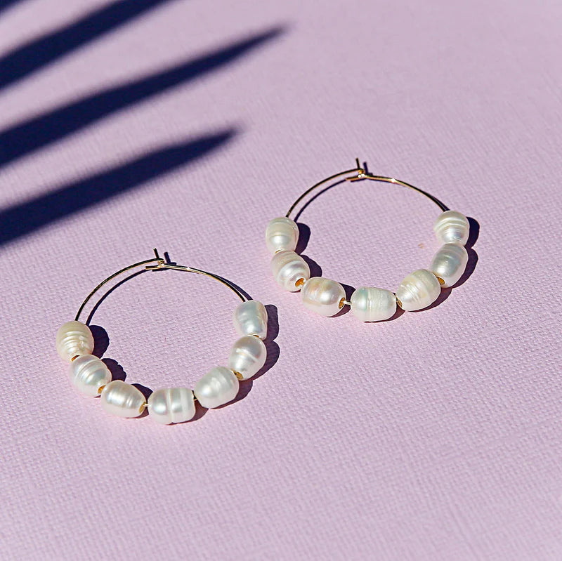 Pearl hoop earrings on a pink background