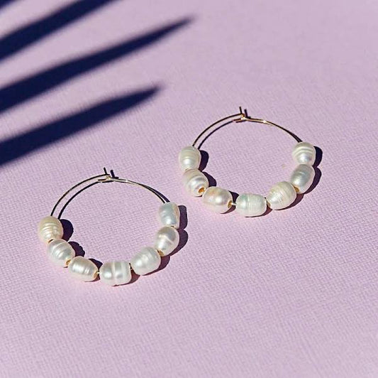 Pearl hoops sit on lilac background.