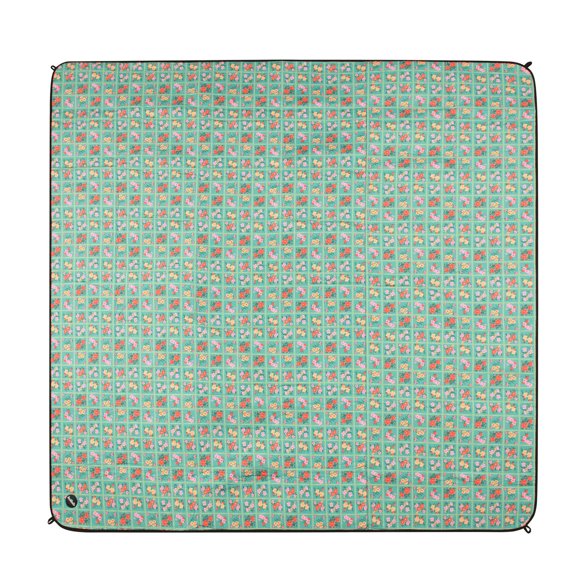 Picnic mat laid out on white background, pattern of mat is floral squares with green background.