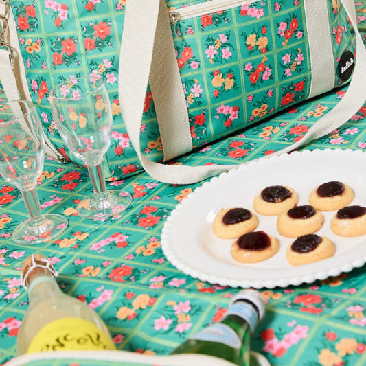 Picnic mat and cooler bag in same print with bottles and biscuits on plate.