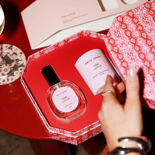 Celia Loves Pink Lotus perfume set with a hand reaching for the bottle on a decorative surface.