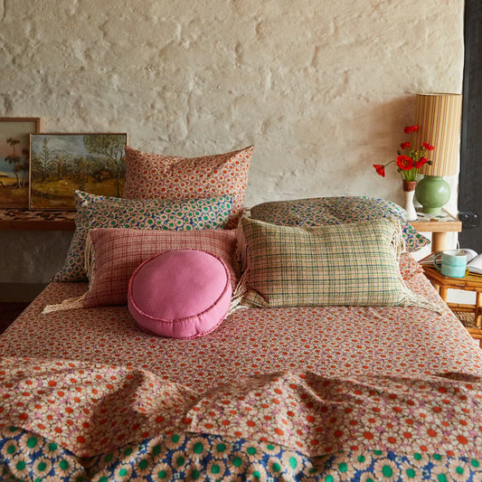 Bed with patterned bedding and pillows in a room with a stone wall.