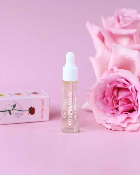 Skincare nail cuticle serum bottle with pink roses and packaging on a pink background.