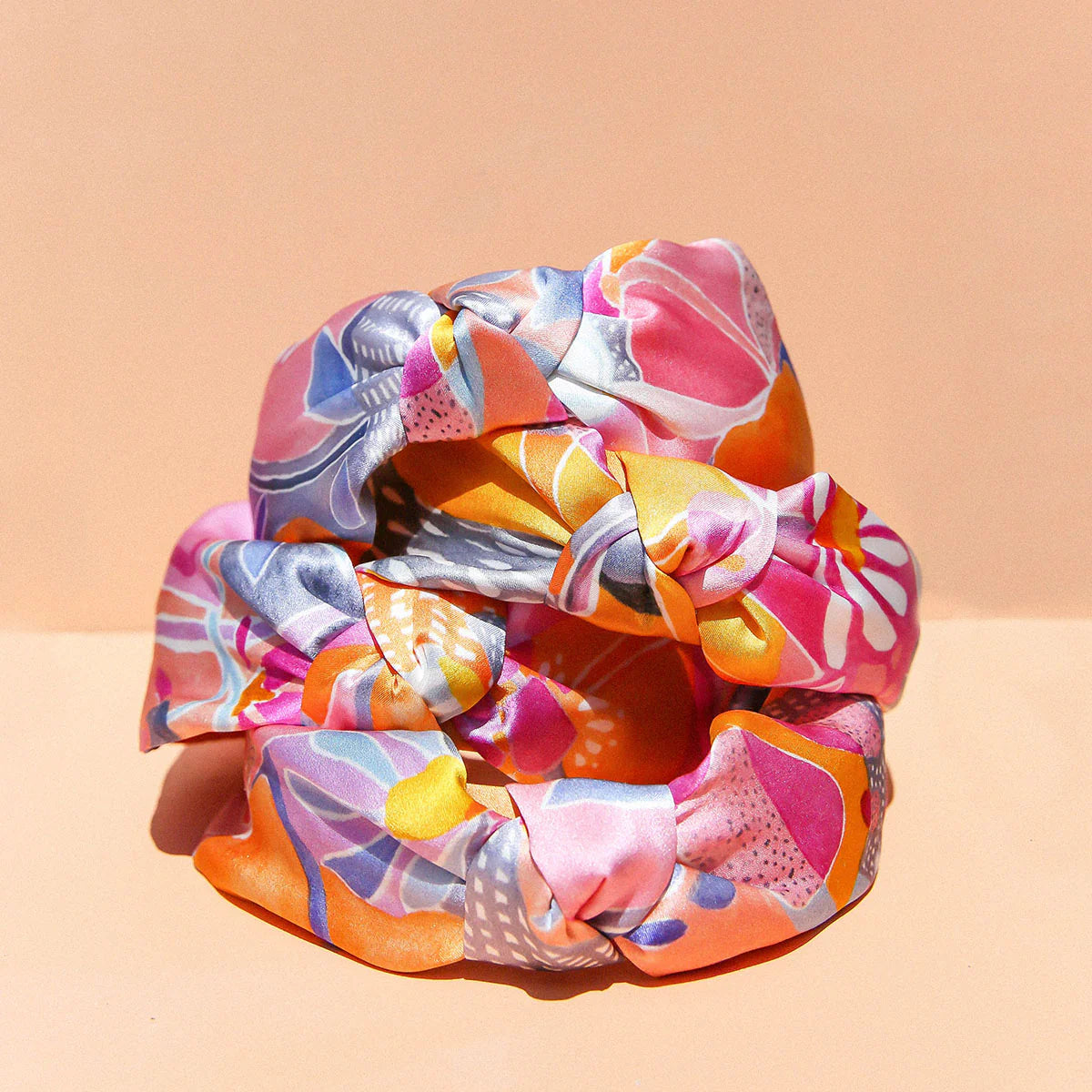 Stack of colourful silk headbangs, colours include orange, blue and pinks.