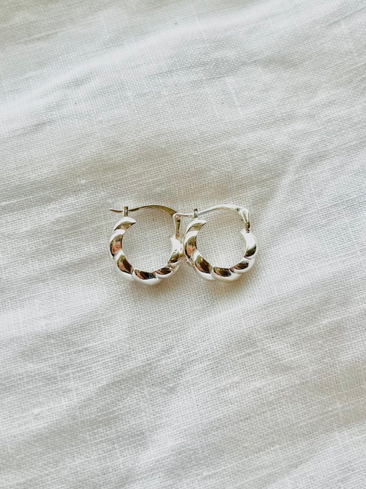 Pair of silver hoop earrings on a light fabric background