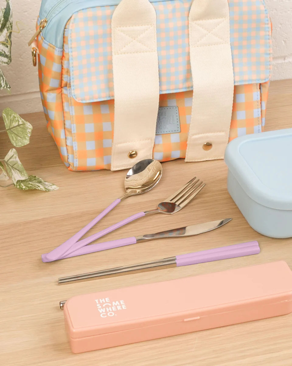 Cutlery set laid out with lunch bag sat in background and lunch container.
