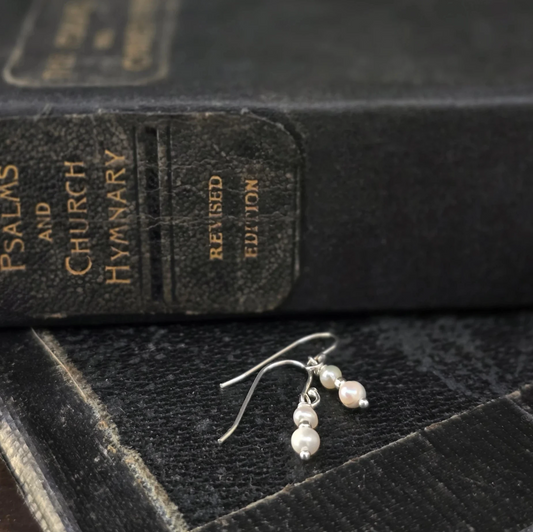 Silver earrings with pearls on a black hymnbook