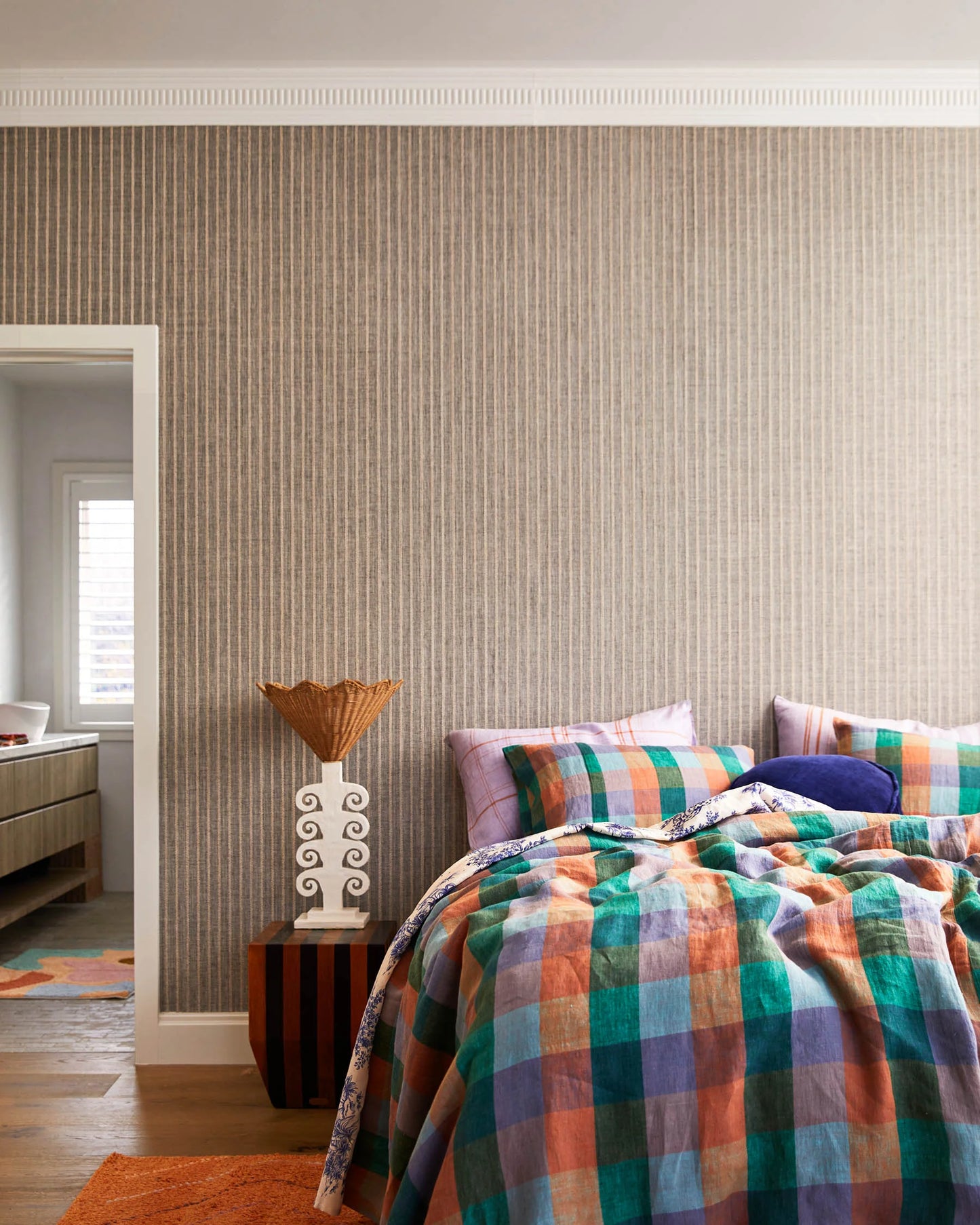 Bedroom with plaid bedding and textured wall, quilt cover features colours including teal, rust, blue and lilac.