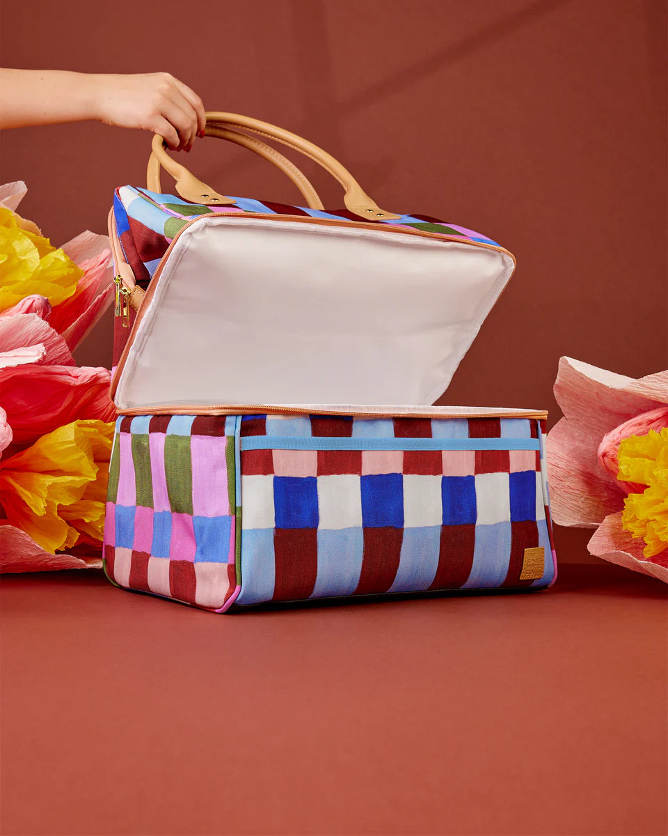 Colorful checkered bag with a hand holding it against a red background