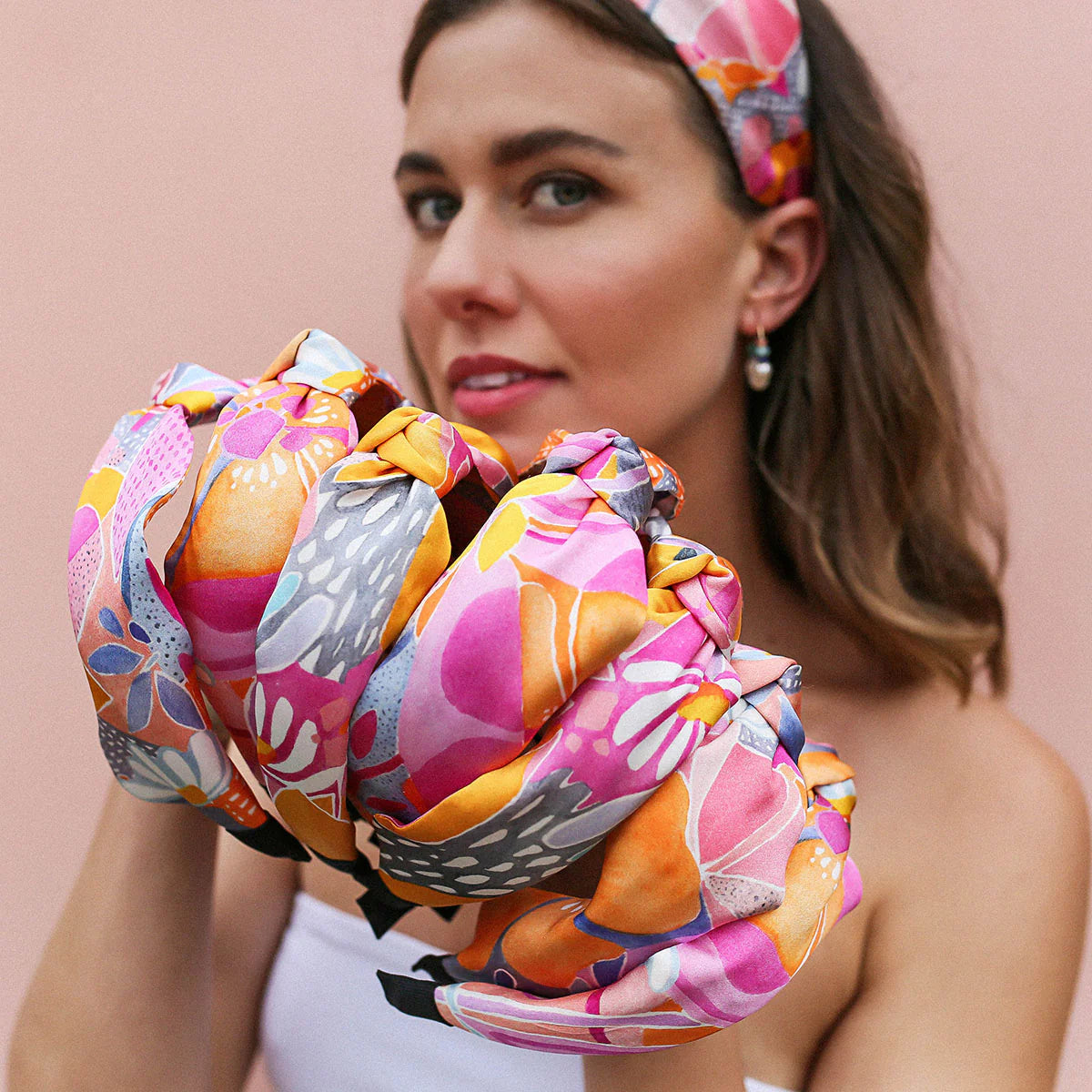 Woman holds stack of silk headbands in same print, but highlights how different each will be positioned in terms of fabric.