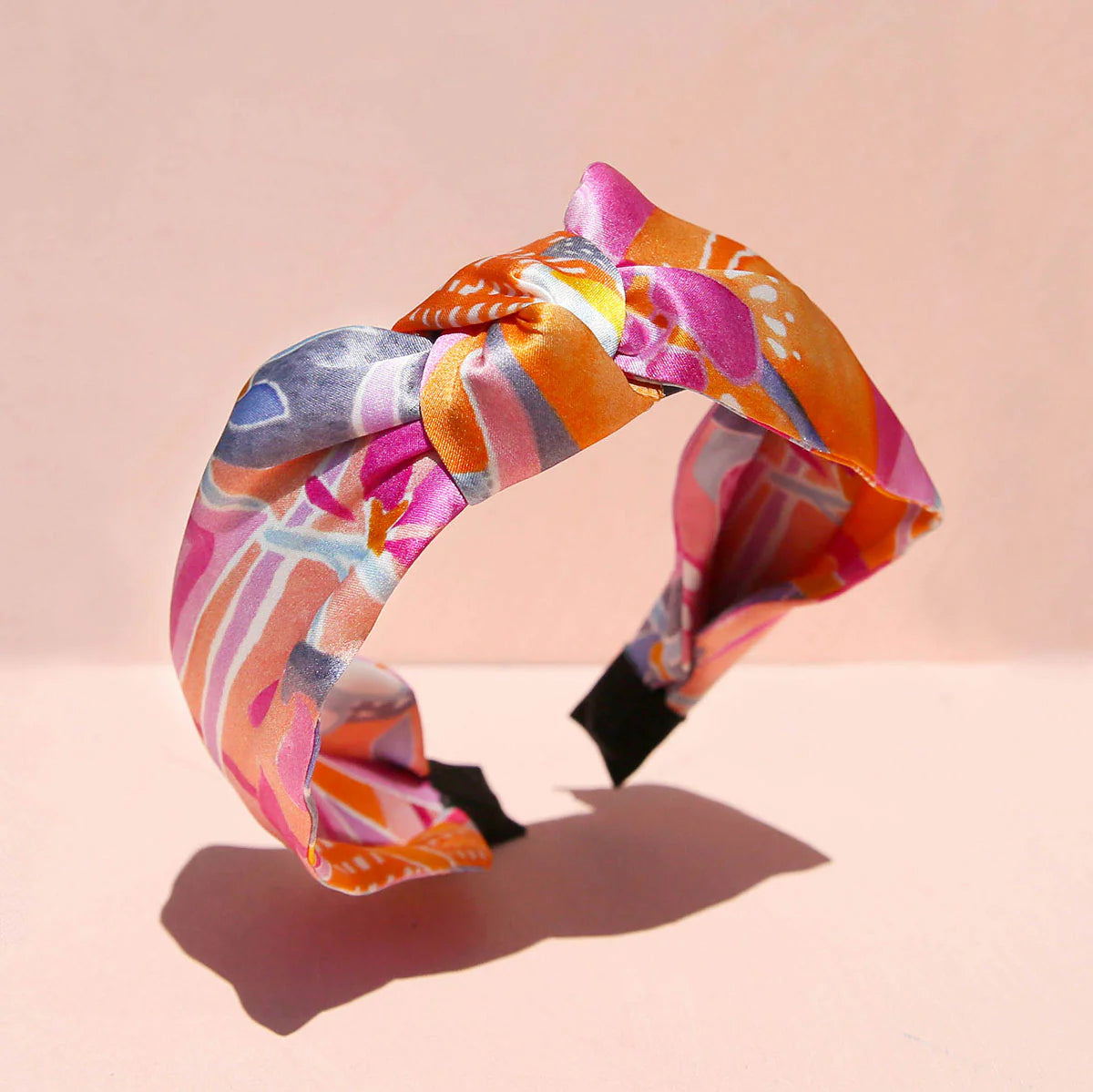 Silk headband with knotted centre, pink background.