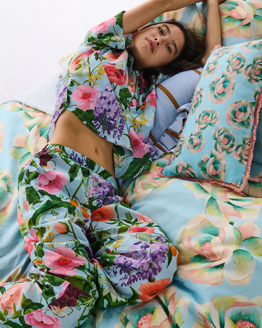 Woman lying on a floral bedspread with colorful pillows