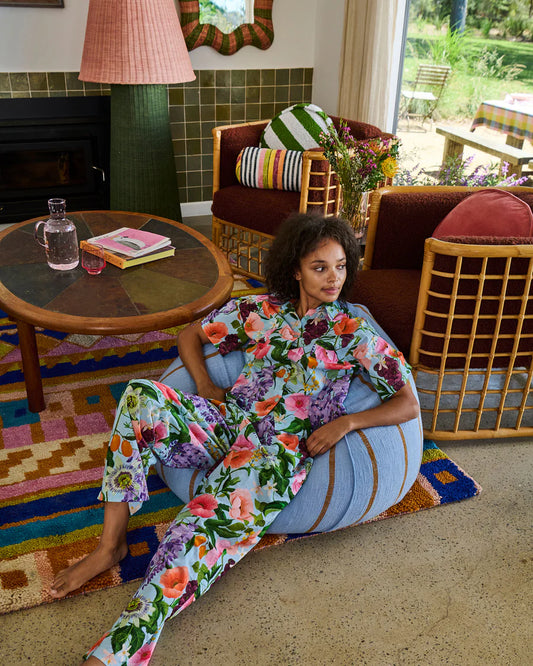 Woman in a floral outfit sitting on a colorful rug in a living room.