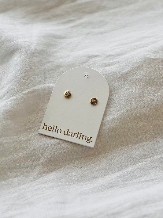 Pair of earrings on a 'hello darling' card against a light fabric background