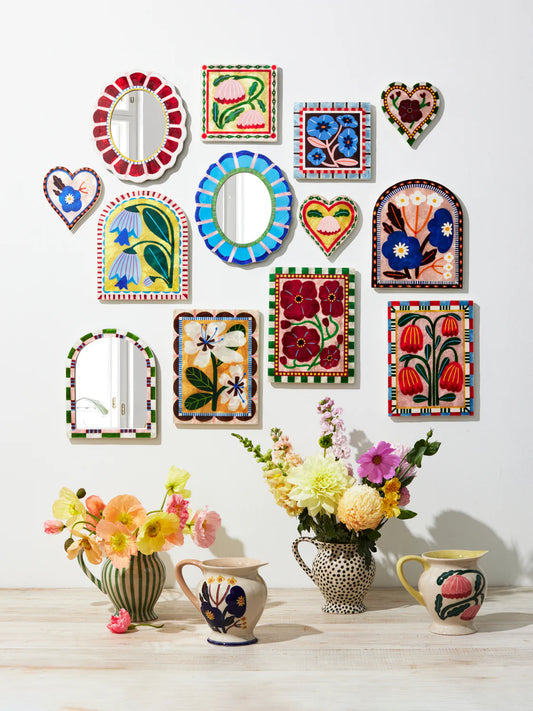 Decorative wall mirrors and floral arrangements on a white background