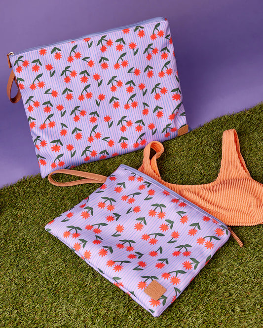 Two floral-patterned pouches on a grassy surface with a purple background