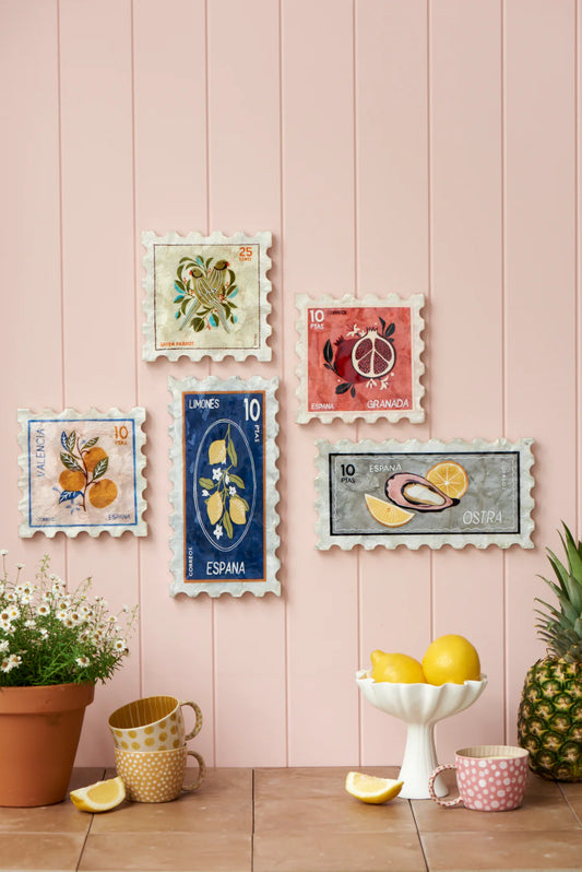 Decorative wall art with colorful stamps on a pink wooden panel wall.